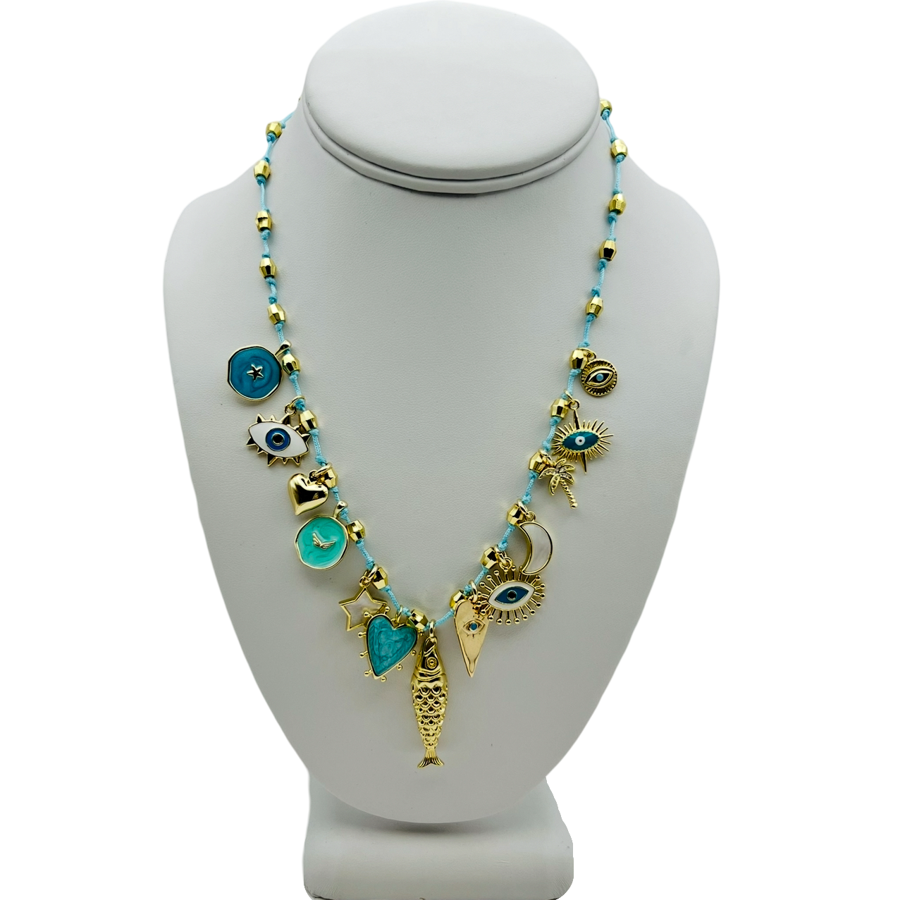 A vacation charm necklace featuring a light blue everyday necklace with gold-filled hardware and various charms, including a fish and a evil eye charms by HOLST+LEE